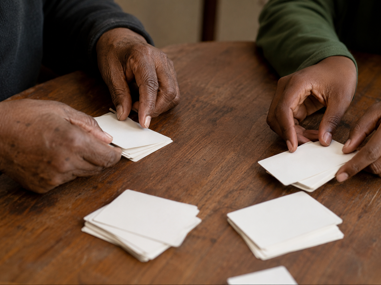 Hands sorting blank cards into small groups on a table during a family values conversation