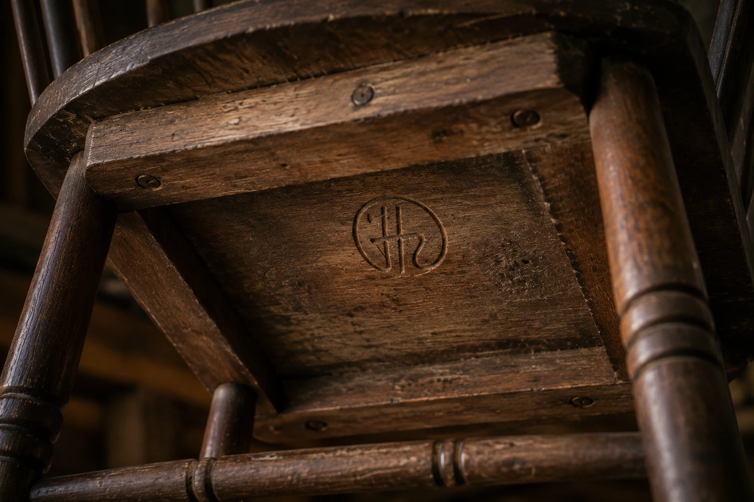The underside of a handmade chair revealing a maker's carved signature and date