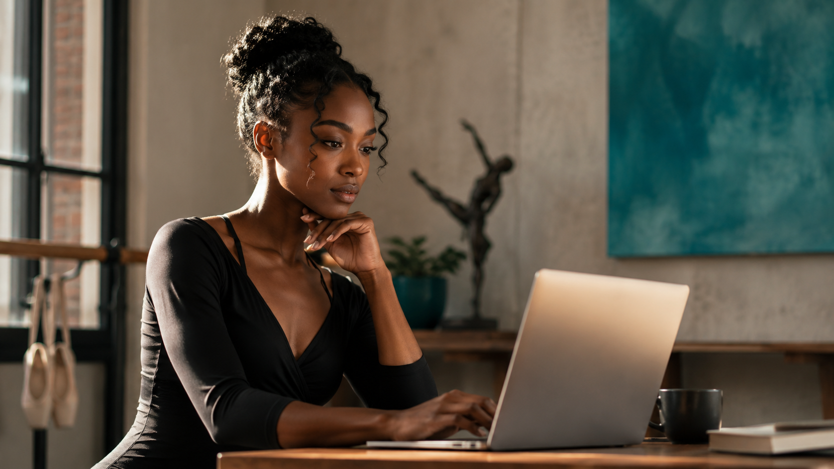 Dancer reviewing her professional website portfolio on a laptop in a studio workspace