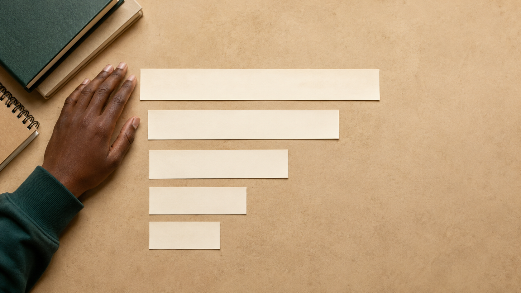 Overhead view of five paper strips of descending length on a ledger-toned desk, with the top two clearly longest, representing the five credit score categories and their relative weight.